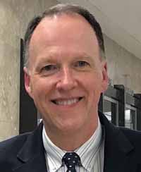 A person in a suit smiling

Description automatically generated